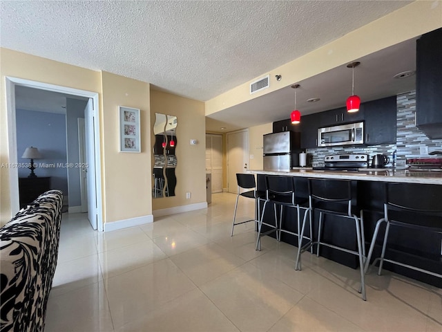 kitchen featuring visible vents, stainless steel appliances, backsplash, and light countertops