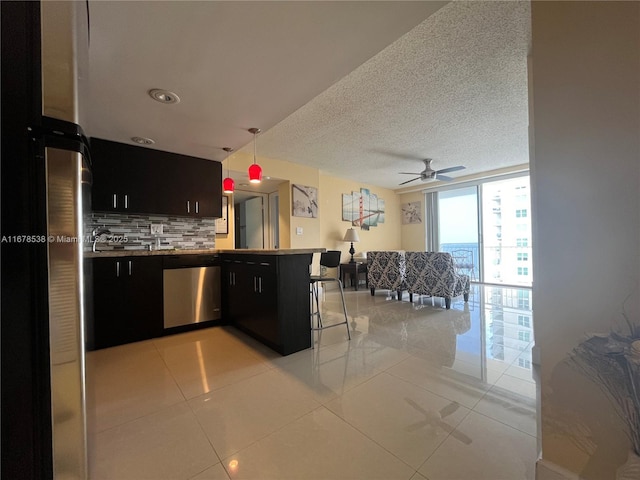 kitchen with hanging light fixtures, backsplash, expansive windows, a textured ceiling, and dishwasher