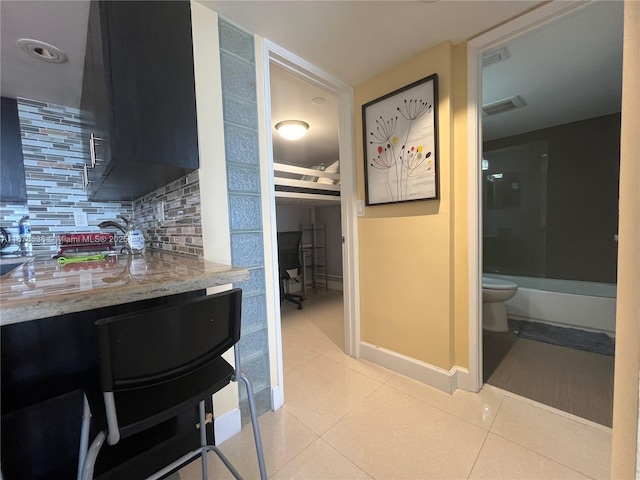 kitchen with light tile patterned floors, baseboards, visible vents, and decorative backsplash