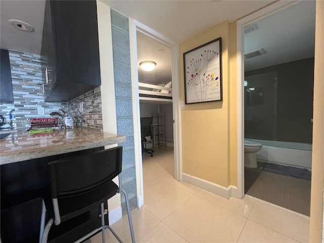 kitchen with light tile patterned floors, visible vents, baseboards, and backsplash