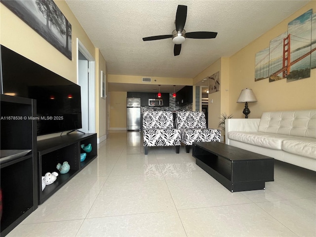 living room with a textured ceiling, ceiling fan, visible vents, and light tile patterned floors