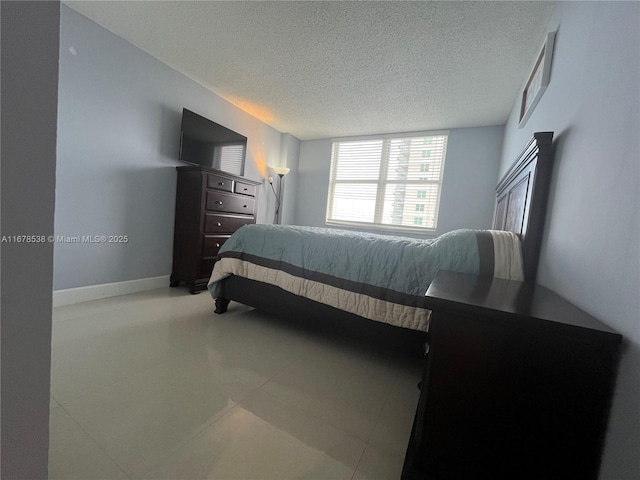 bedroom featuring baseboards, a textured ceiling, and light tile patterned flooring