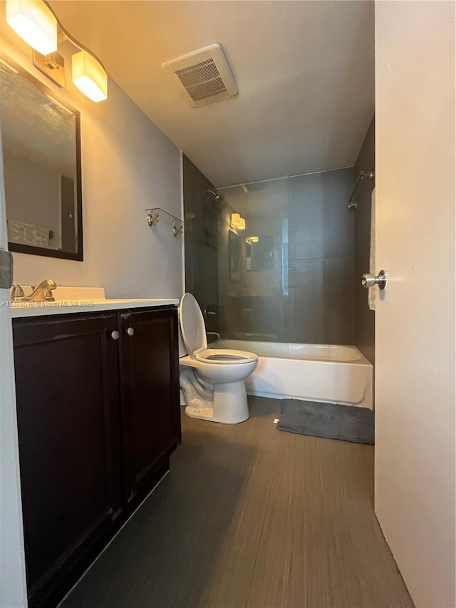 bathroom with visible vents, toilet, shower / tub combination, wood finished floors, and vanity