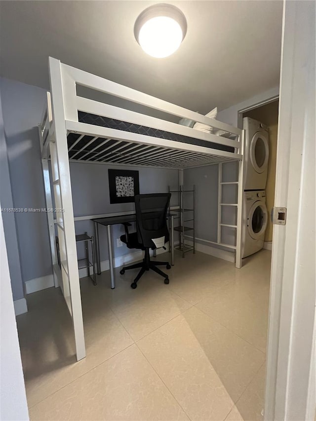 bedroom with baseboards and stacked washer / drying machine