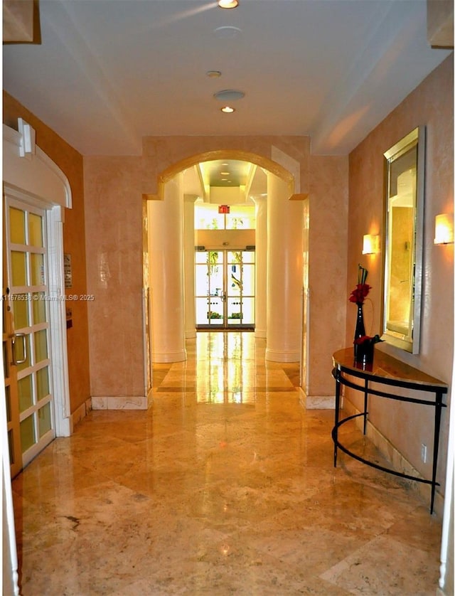 hallway with baseboards, arched walkways, and marble finish floor