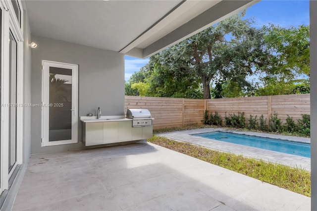 view of pool featuring a patio area, an outdoor kitchen, a grill, and a fenced backyard