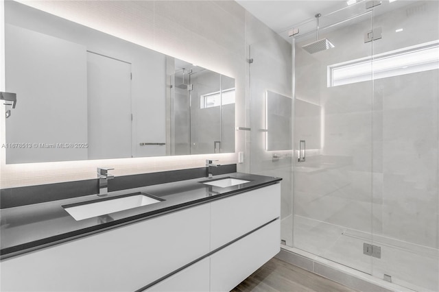 full bathroom with a sink, wood finished floors, a stall shower, and double vanity