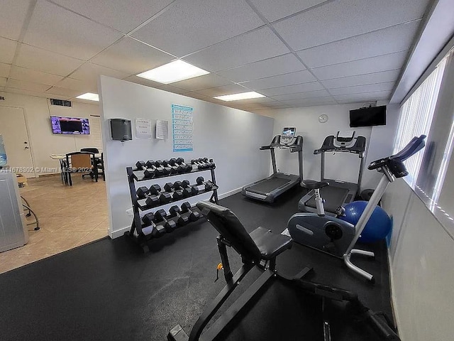 exercise room with a drop ceiling and tile patterned flooring