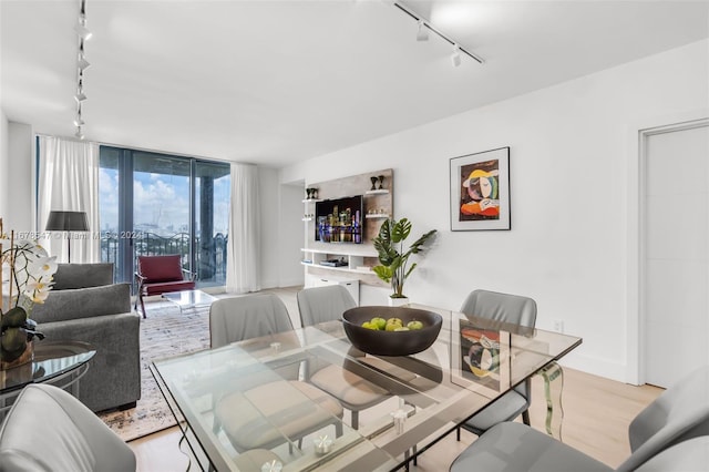 dining area with rail lighting and light hardwood / wood-style floors