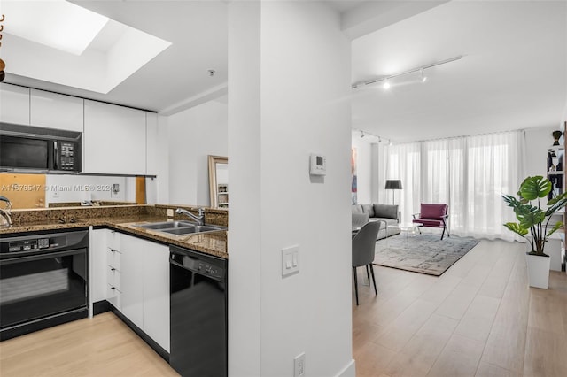 kitchen featuring black appliances, light wood-type flooring, and white cabinetry