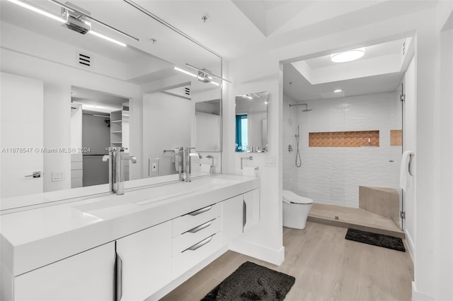 bathroom featuring vanity, toilet, a tile shower, and wood-type flooring