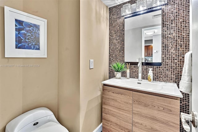 bathroom with vanity, toilet, and tasteful backsplash