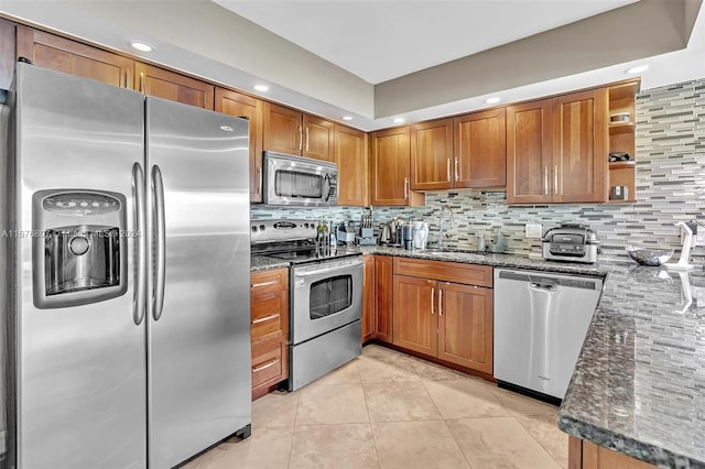 kitchen with stainless steel appliances, sink, dark stone counters, and backsplash