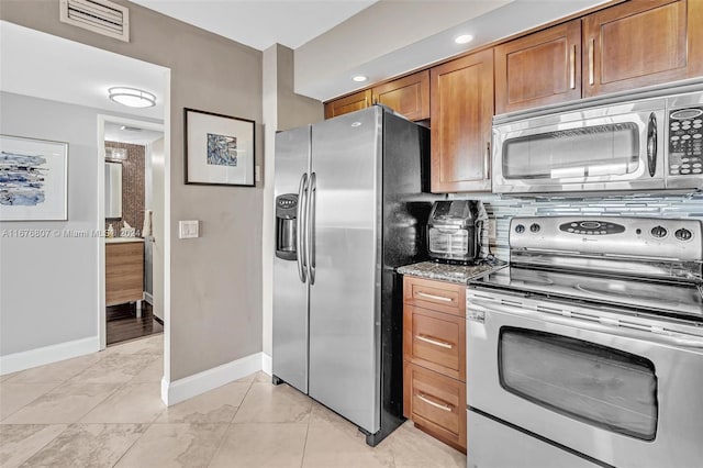 kitchen with tasteful backsplash, stainless steel appliances, stone counters, and light tile patterned floors