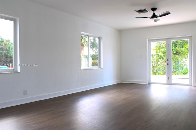 spare room featuring a healthy amount of sunlight, ceiling fan, and dark hardwood / wood-style flooring