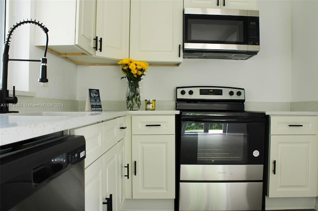 kitchen featuring appliances with stainless steel finishes, light stone counters, and white cabinets