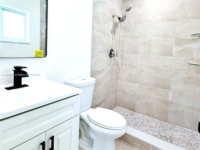 bathroom featuring vanity, a tile shower, and toilet