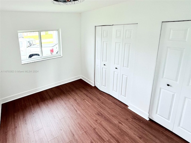 unfurnished bedroom with dark wood-type flooring and vaulted ceiling