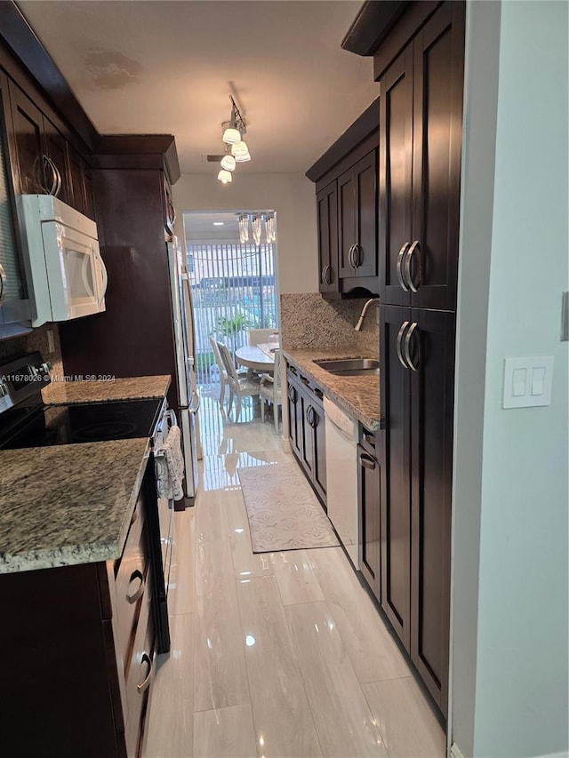 kitchen with sink, light stone countertops, and white appliances