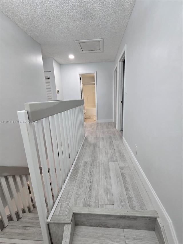 hallway featuring a textured ceiling and light wood-type flooring