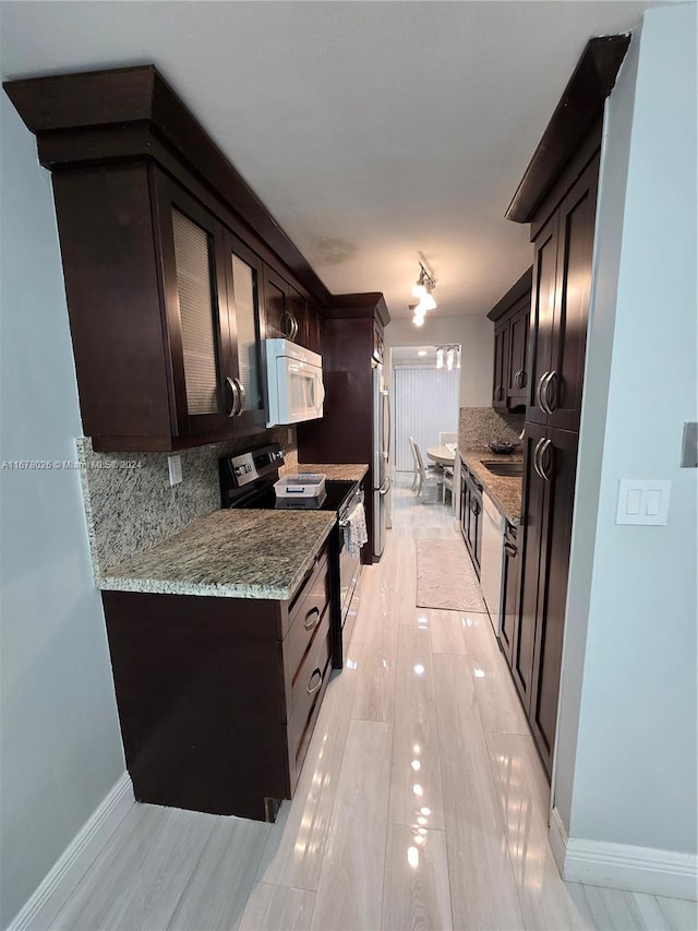 kitchen featuring stainless steel fridge, backsplash, sink, black electric range, and light stone counters