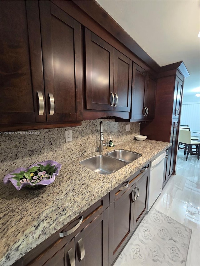 kitchen featuring sink, white dishwasher, dark brown cabinets, light stone counters, and decorative backsplash