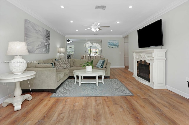 living room with crown molding, light hardwood / wood-style flooring, and ceiling fan