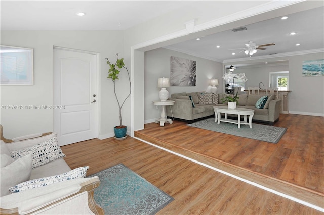 living room featuring ornamental molding, vaulted ceiling, wood-type flooring, and ceiling fan