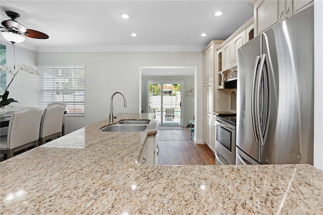 kitchen featuring light stone countertops, appliances with stainless steel finishes, sink, ornamental molding, and light hardwood / wood-style flooring