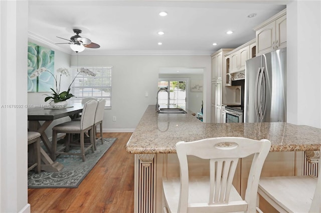 kitchen with cream cabinetry, dark hardwood / wood-style floors, sink, crown molding, and appliances with stainless steel finishes