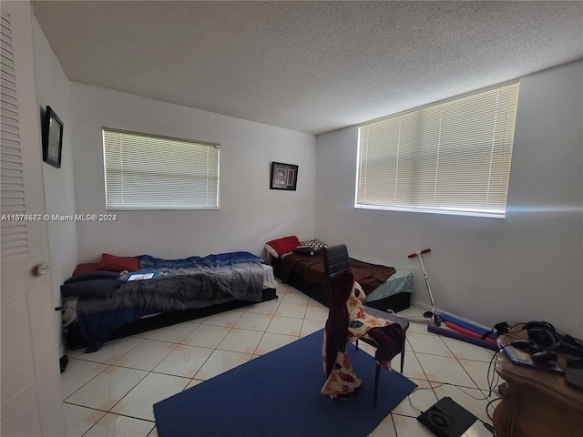 bedroom featuring multiple windows, a textured ceiling, and light tile patterned floors