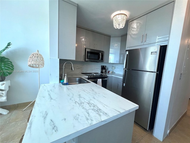 kitchen featuring gray cabinetry, sink, decorative backsplash, decorative light fixtures, and stainless steel appliances