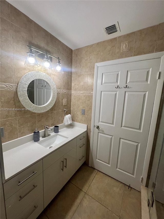 bathroom with tile patterned flooring, vanity, and tile walls