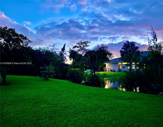 yard at dusk featuring a water view