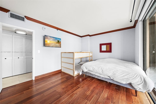 bedroom with crown molding, hardwood / wood-style flooring, and a closet