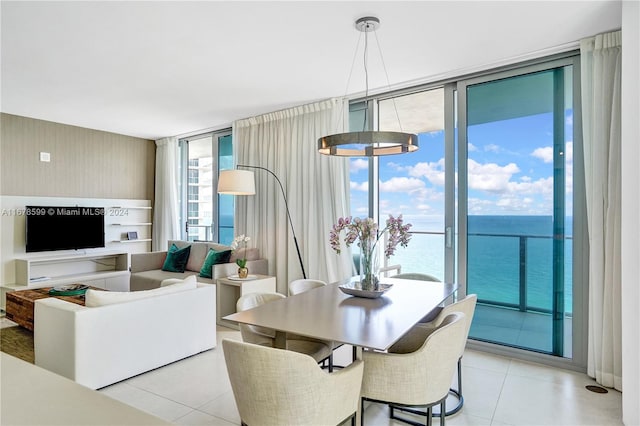 dining room featuring expansive windows, a notable chandelier, a water view, and a healthy amount of sunlight