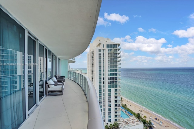 balcony featuring a water view and a beach view