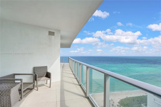 balcony featuring a water view and a beach view