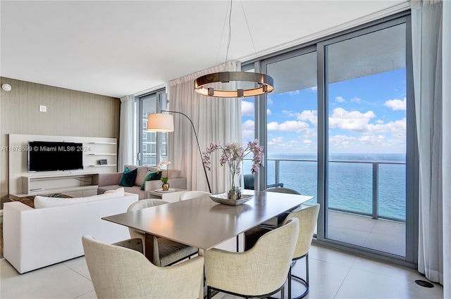 dining area featuring a chandelier, a water view, and expansive windows