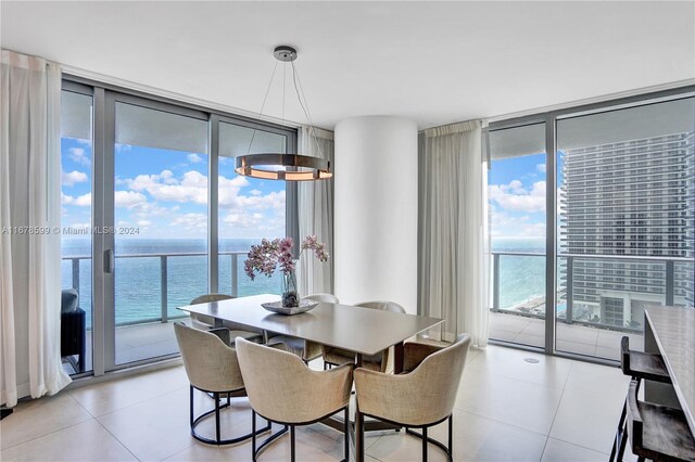 dining space featuring a wall of windows, a water view, and light tile patterned floors