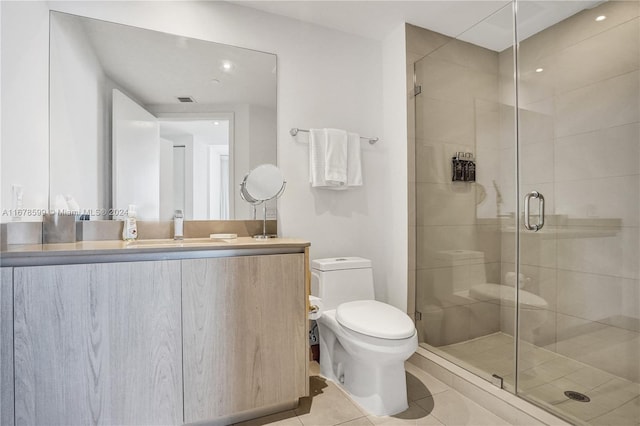 bathroom featuring vanity, toilet, tile patterned flooring, and a shower with door