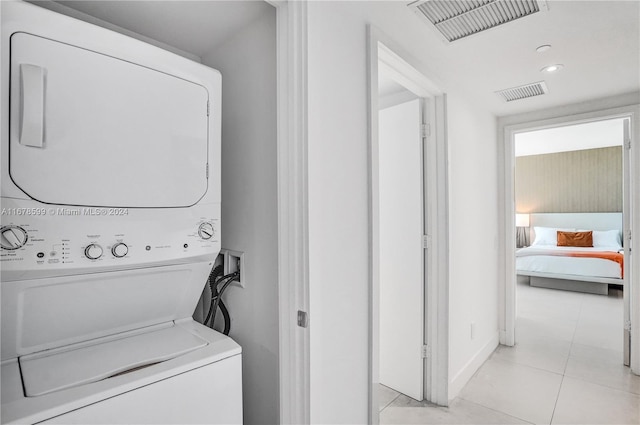 laundry area featuring light tile patterned floors and stacked washer and dryer