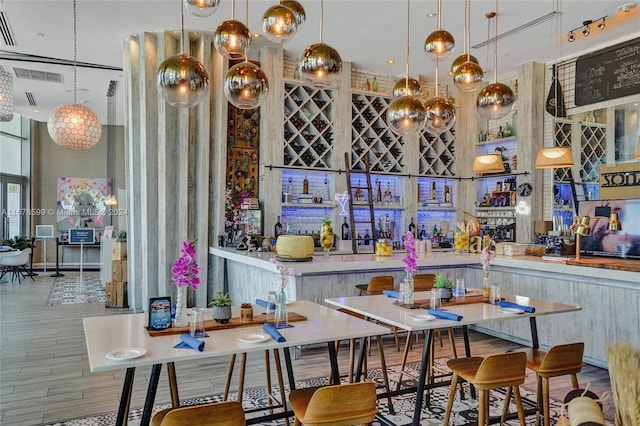 bar with hardwood / wood-style flooring, decorative light fixtures, and a high ceiling