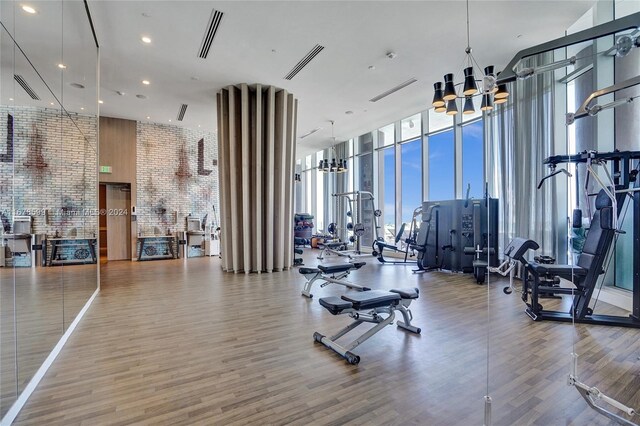 gym featuring expansive windows, hardwood / wood-style flooring, and a high ceiling