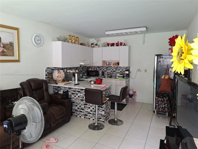 kitchen with backsplash, light tile patterned floors, and white cabinets