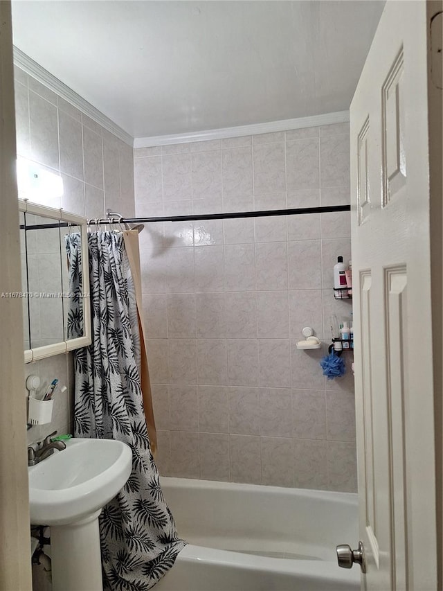 bathroom with shower / bath combo with shower curtain, crown molding, sink, and tile walls