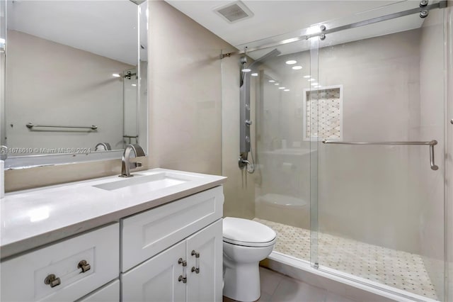 bathroom featuring vanity, toilet, tile patterned floors, and a shower with shower door