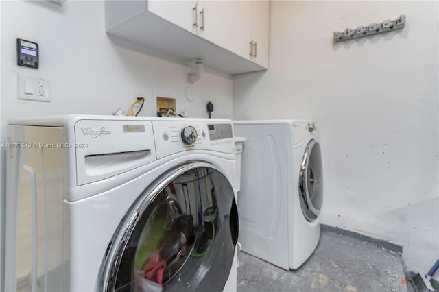 clothes washing area with washing machine and dryer and cabinets