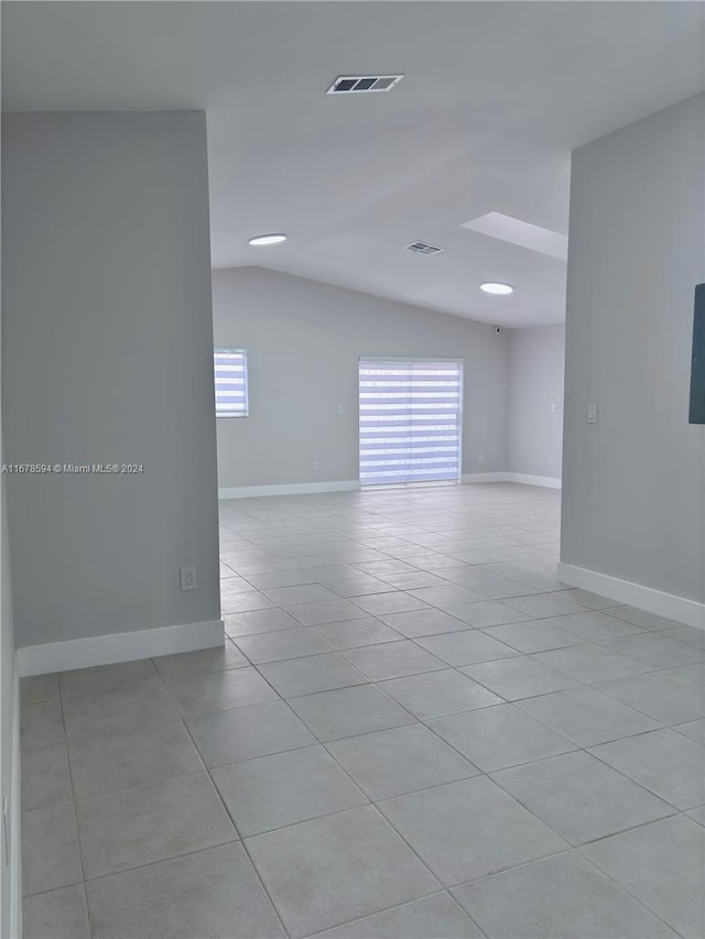 tiled empty room featuring lofted ceiling