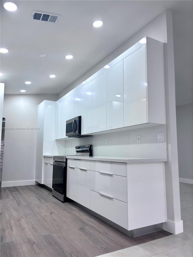 kitchen with white cabinetry, appliances with stainless steel finishes, and light hardwood / wood-style flooring